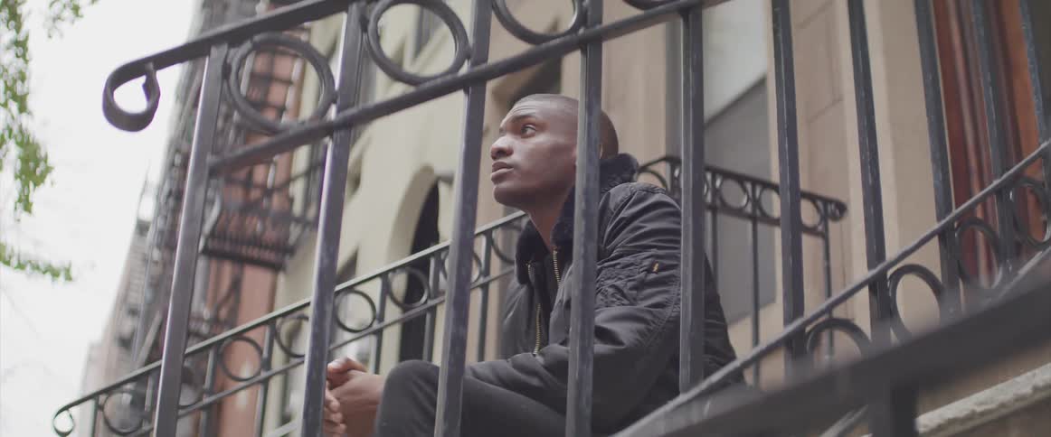 A man sits on the front stoop of a brownstone