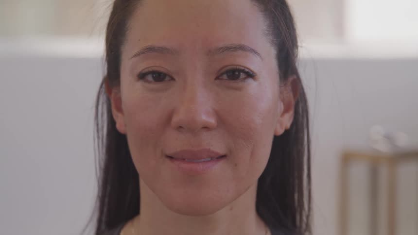 Woman in room opens her eyes and smiles at the camera