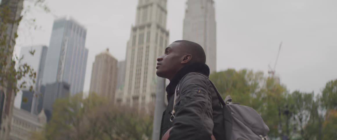 A teenager holding a basketball stands and looks at the skyscrapers