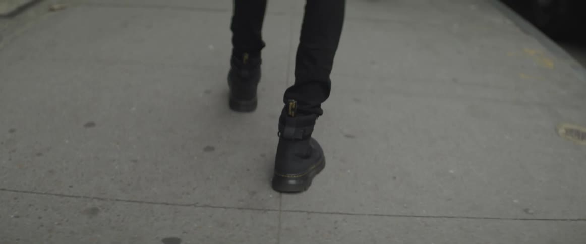 Person wearing boots walks down the street
