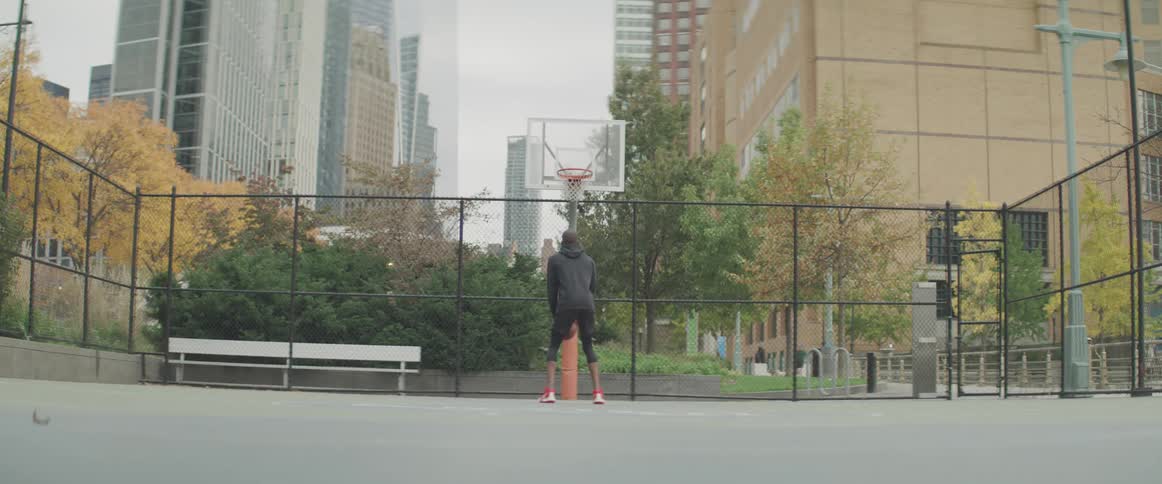 Black basketball player takes a free throw in the public basketball court
