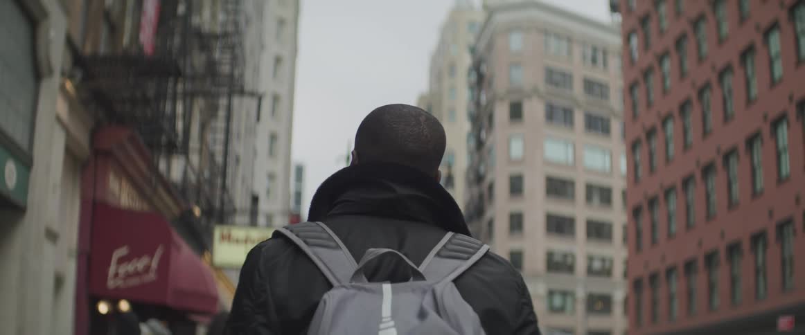 A man walks through an urban area with high rise buildings