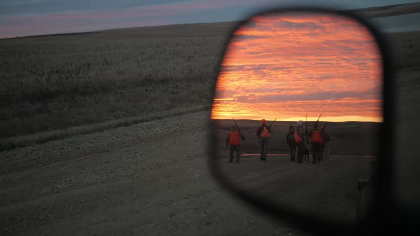 People can be seen in a rear view mirror holding guns