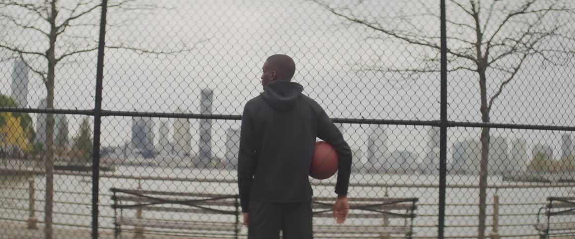 A teenager holding a basket ball looks at the city skyline