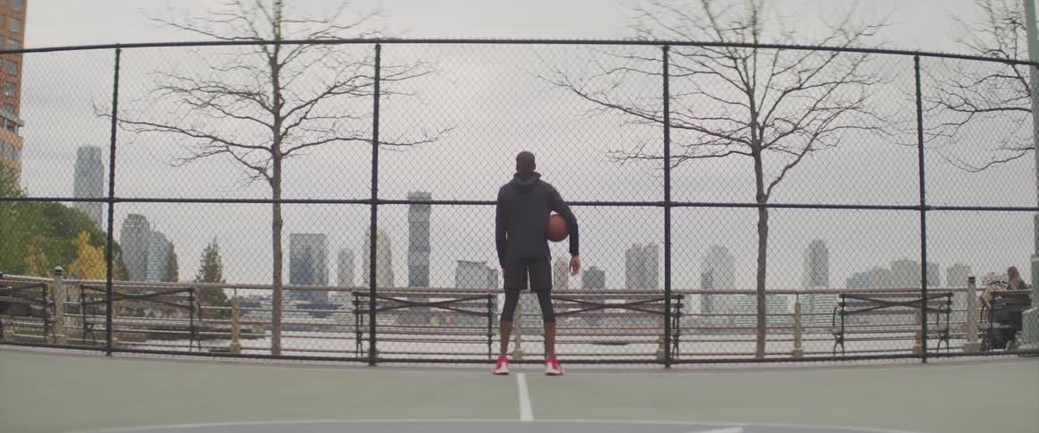 Man holding basketball on a court in park at city