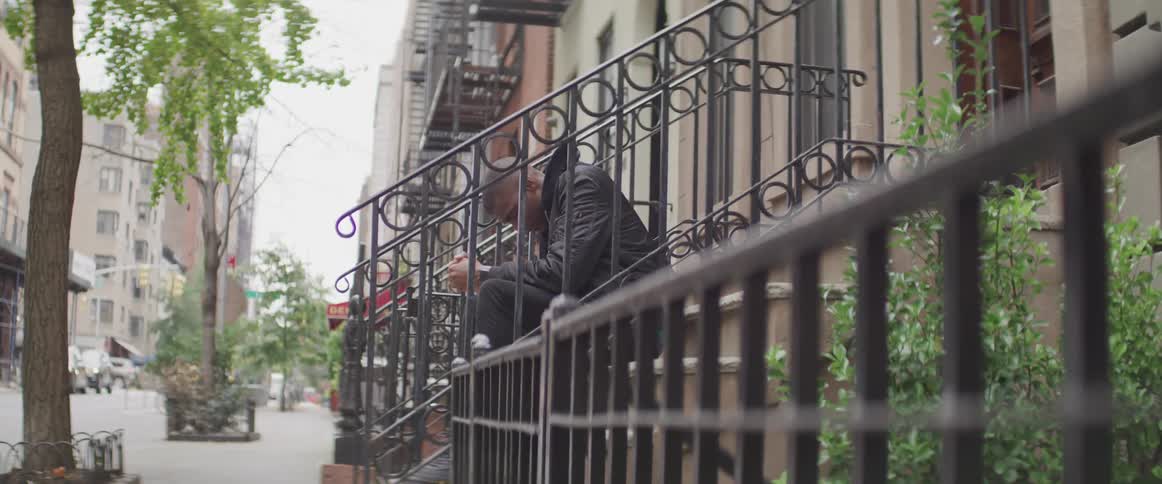 A man sits on front steps of a city building holding his head down