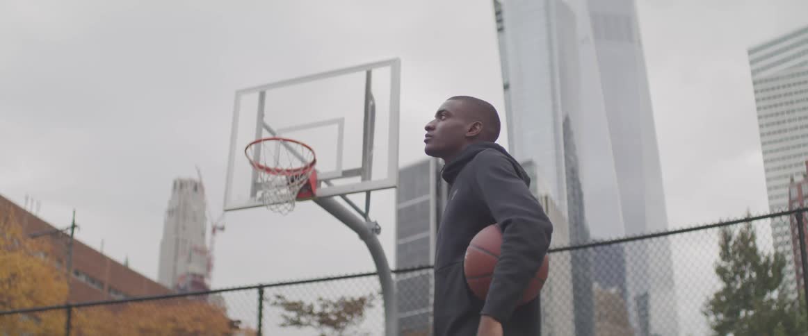 A man stands in the court holding a basketball