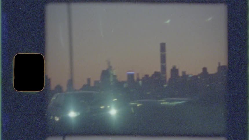 Cars traveling in both directions on a city highway with skyscrapers and city skyline behind