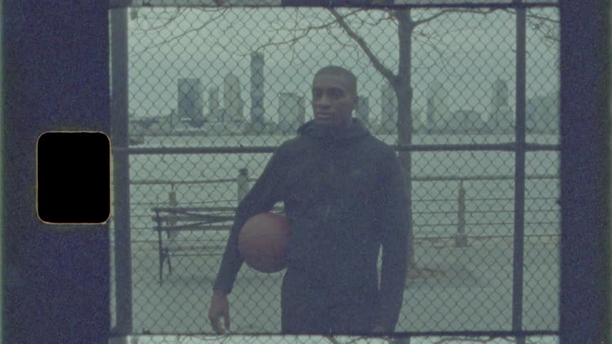 A man stands holding a basketball in a public park