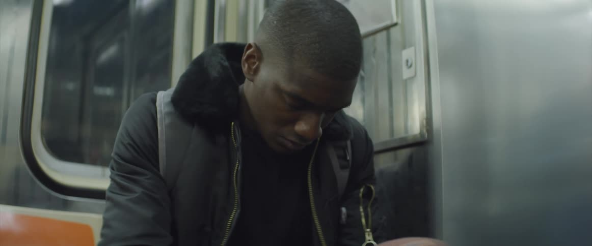 Male looking depressed sitting on moving subway train holding and spinning a basketball in his hands while looking down