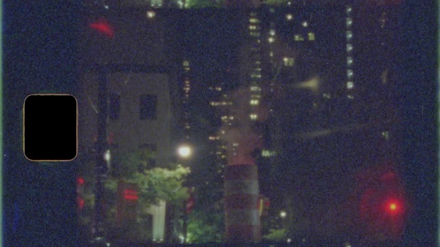 Smoke rises from an orange and white traffic cone on a city sidewalk in front of apartment buildings