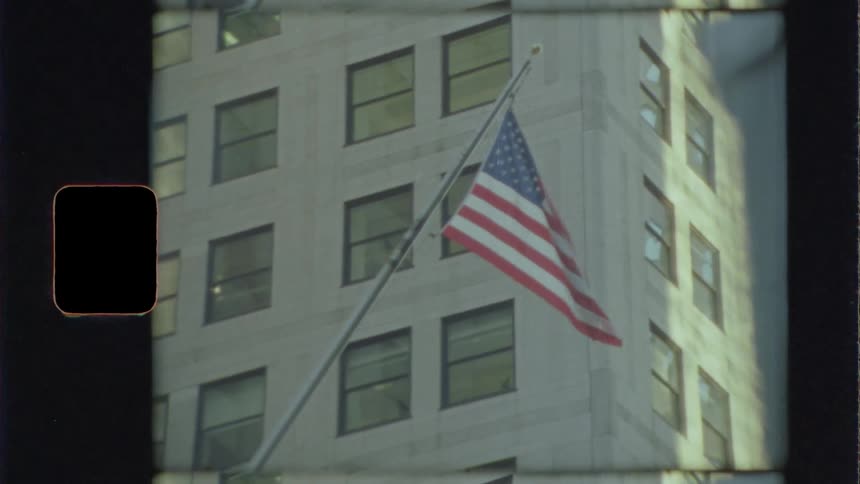 American flag flying in the wind next to a white building