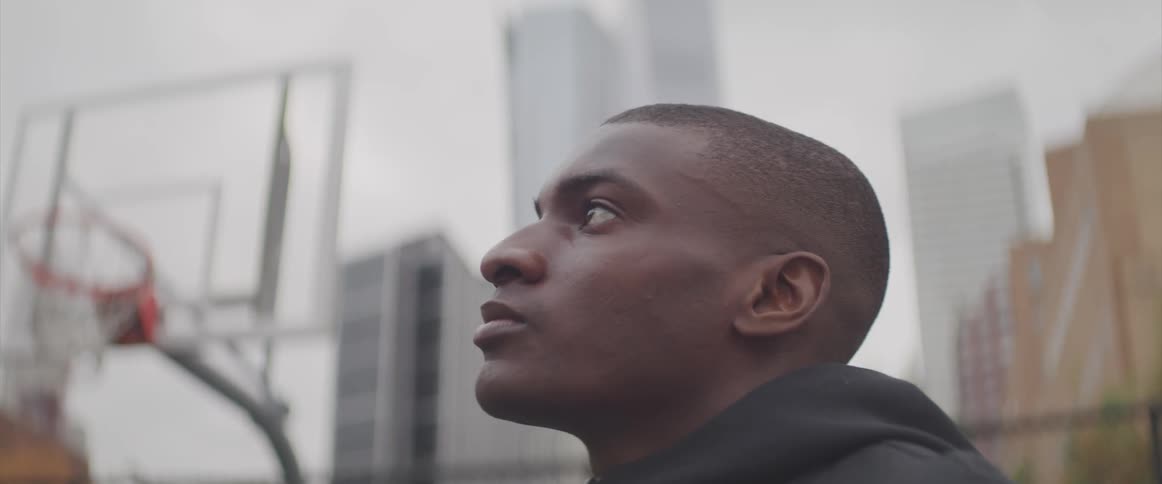 A man looking up at the sky while standing on an outdoors basketball court