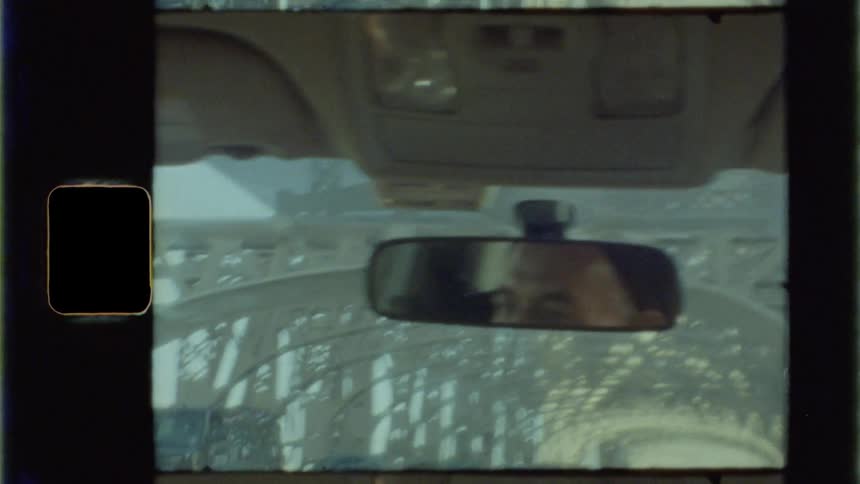 The rearview mirror reflects the drivers head as he travels over a bridge