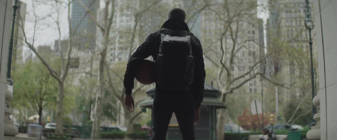 A man stands in center city holding a motorcycle helmet