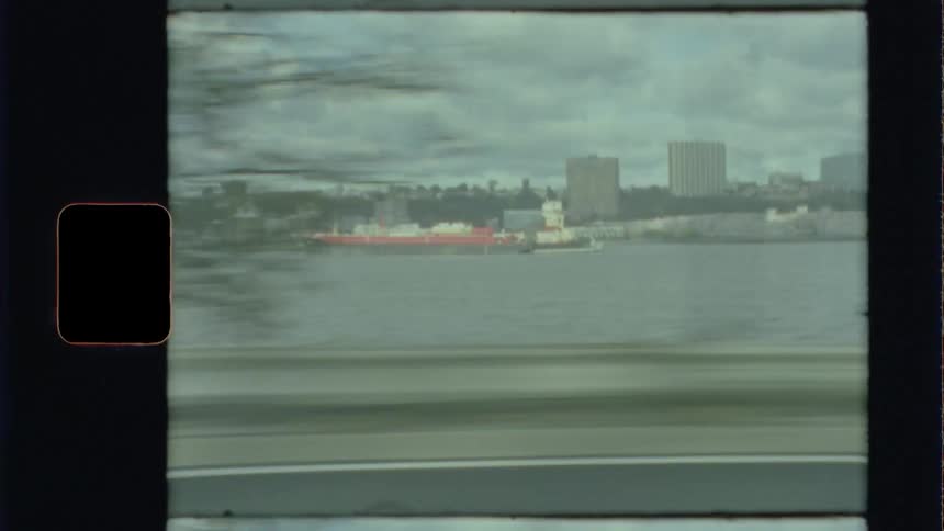 A boat seen out of a vehicle window travels on the water