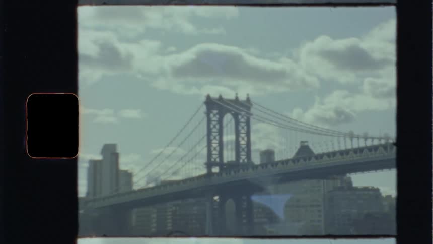 Cars driving past a bridge with the skyline in the background