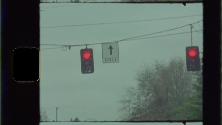 Bird flying across a vintage red light traffic signal hanging from a cable