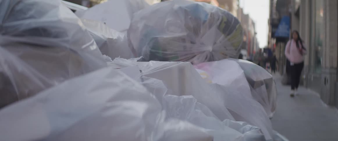 White trash bags stacked on a walkway outside a building