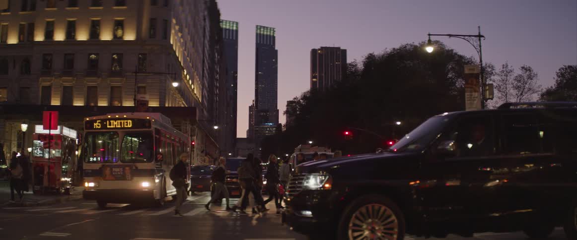 A bike rider crosses a city intersection ahead of vehicles