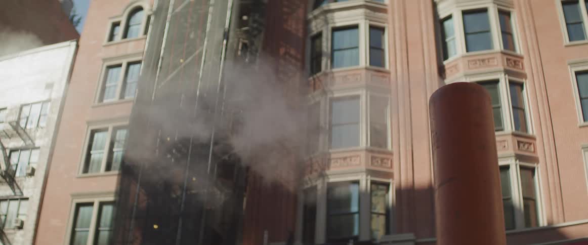 Steam wafts out of a large pipe in a neighborhood in the city