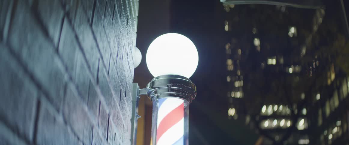 The barbers pole is lit on the side of the building