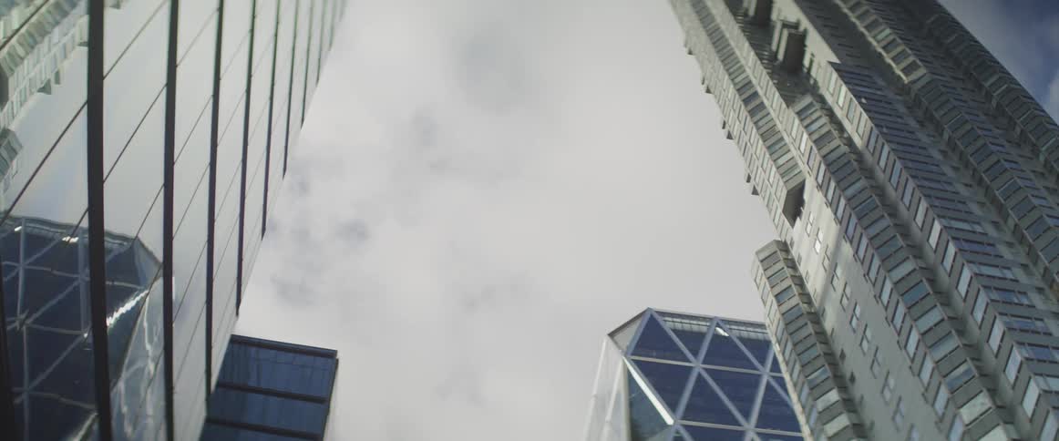 Clouds passing by overhead are reflected in glass of skyscrapers