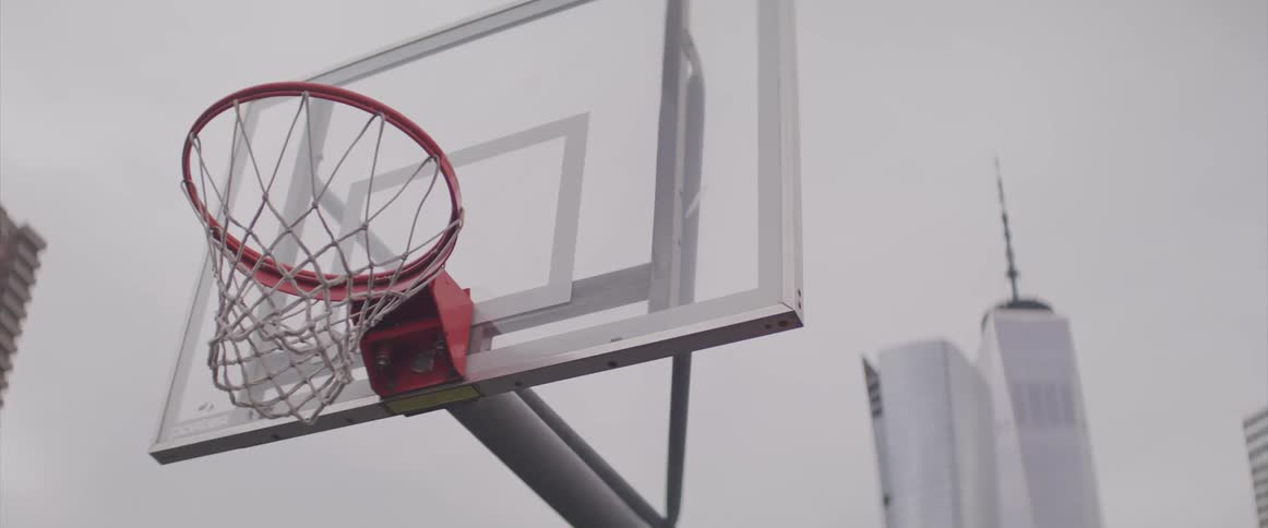 A basketball hoop with buildings and skyscrapers in the background