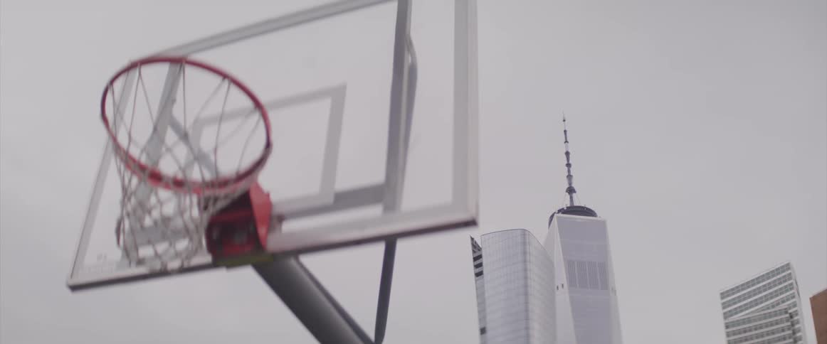 A basketball court has views of tall skyscrapers in the background