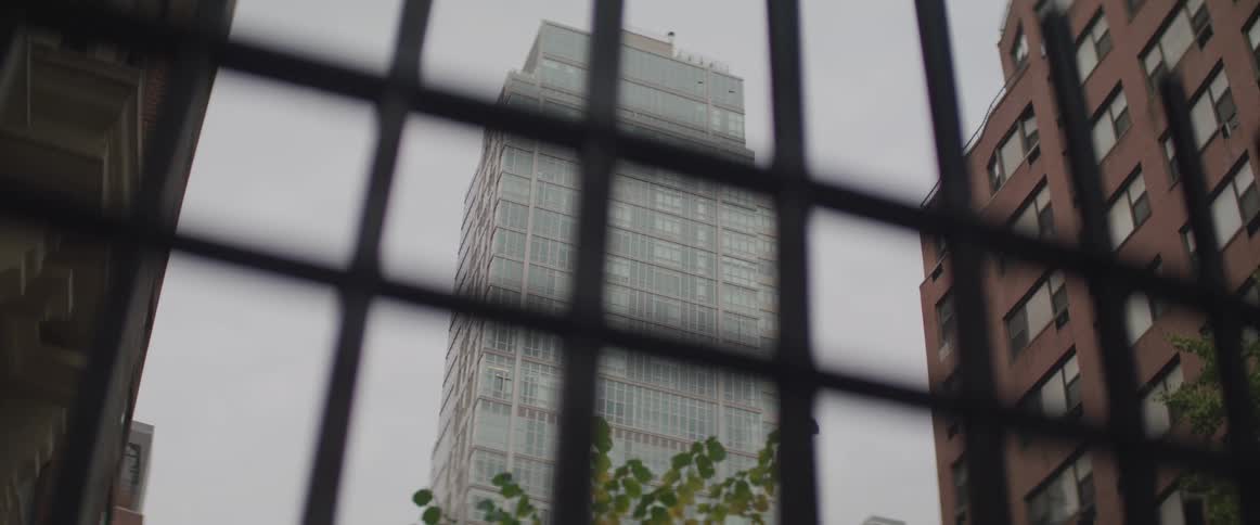 A skyscraper in a city seen through a fence