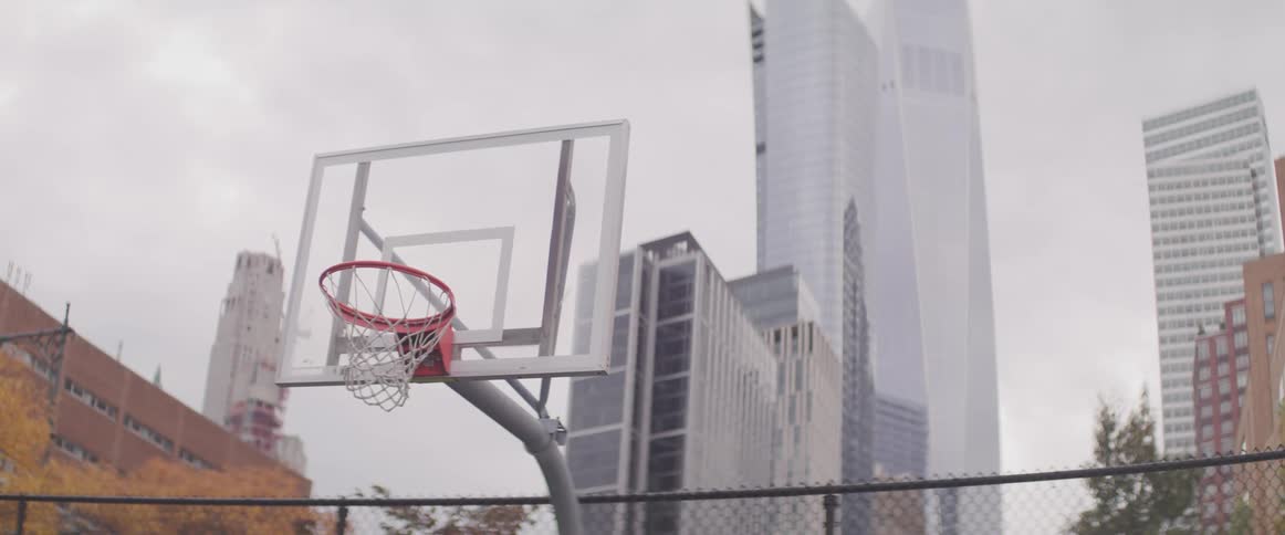 A basketball hoop in front of skyscrapers in a city