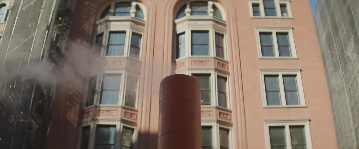 The steam rises from the chimney in front of the apartment building
