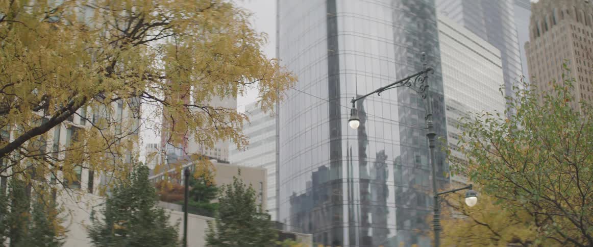 The glass facade of a skyscraper reflects the surrounding buildings in a city