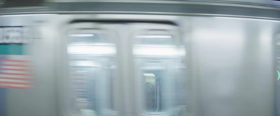 People stand on a train as another train passes by