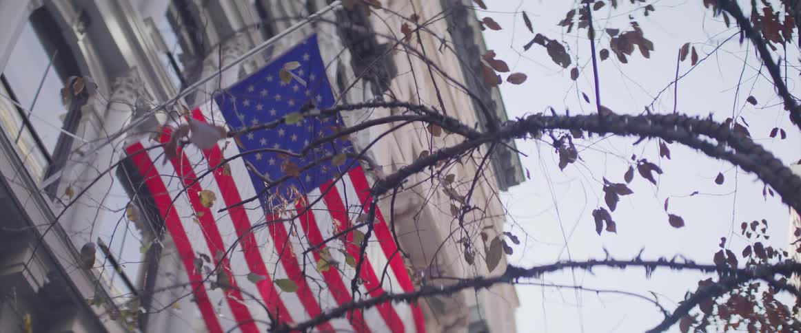 The flag blows in the wind on the side of the building