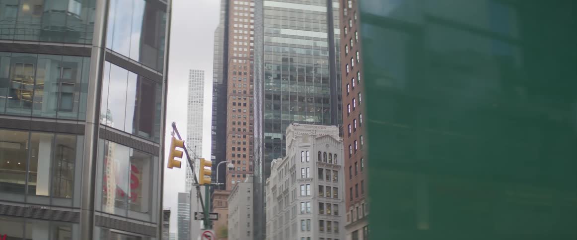 A city street with buildings traffic lights and the sky in the background