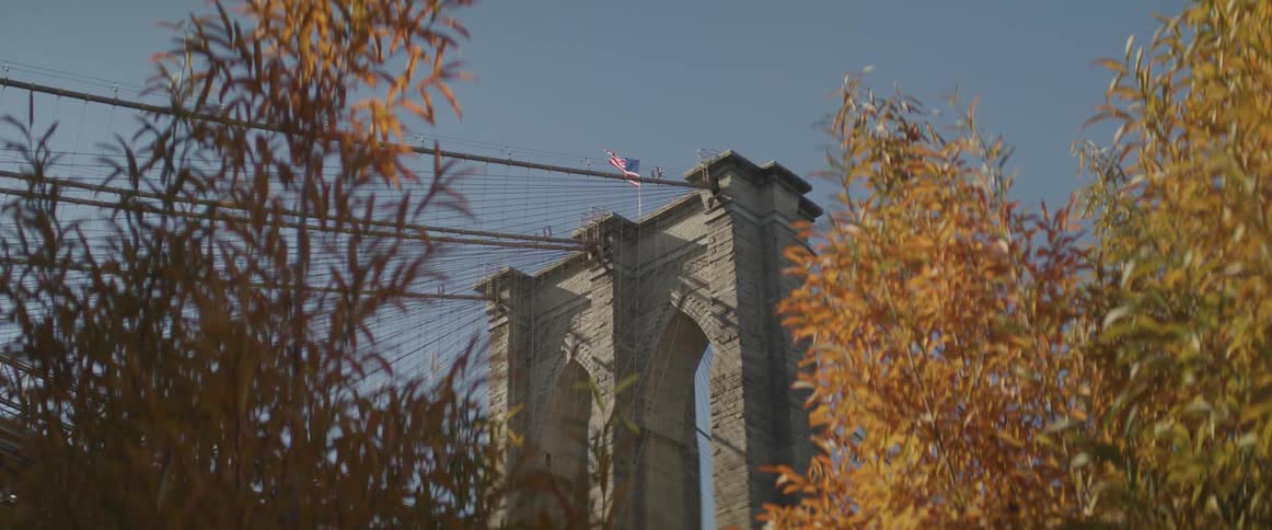 An american flag flies on top of a suspension bridge