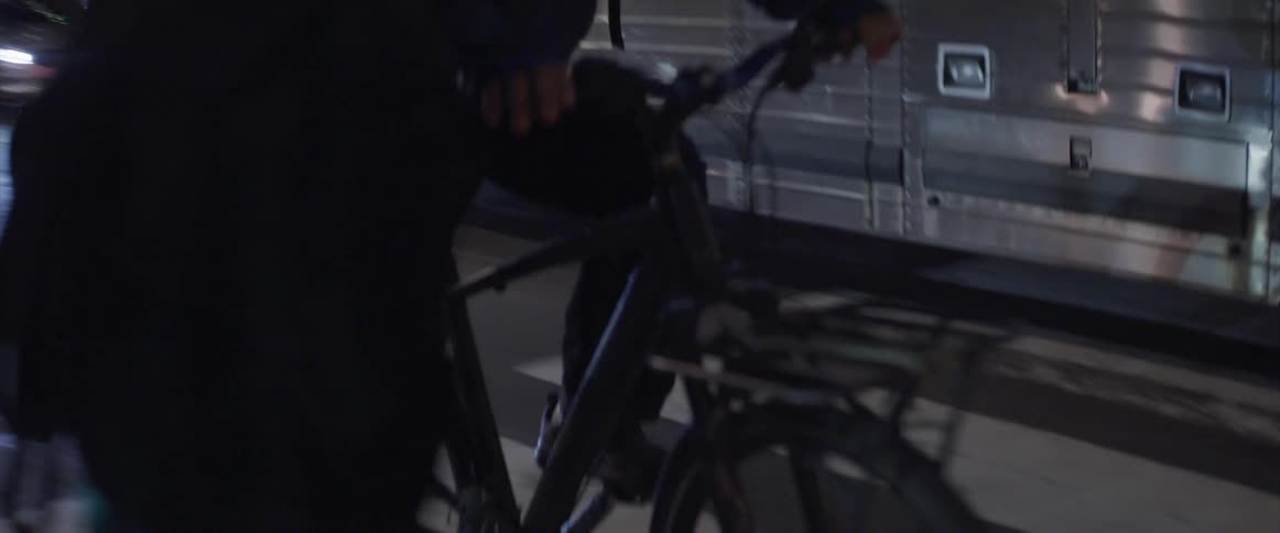 Bicyclist rides down the road as a bus and pedestrians go by