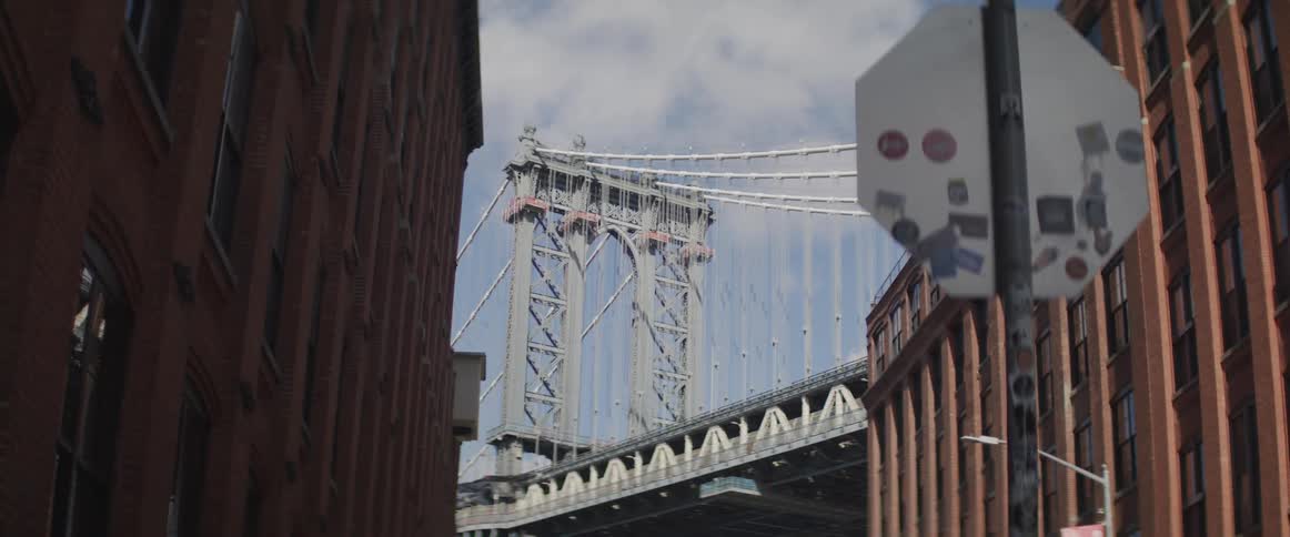 A suspension bridge visible between two large city buildings