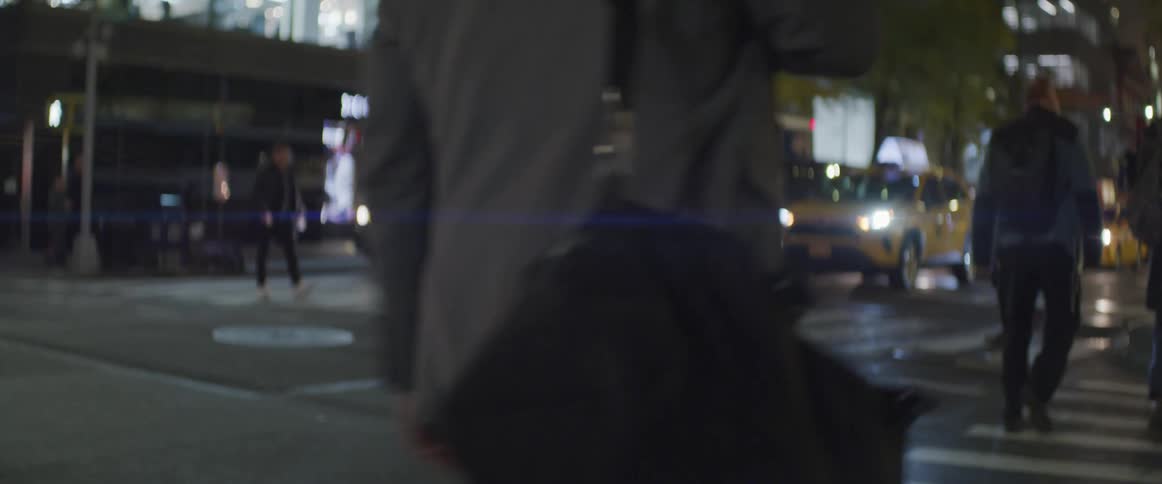 Pedestrians cross street downtown at night