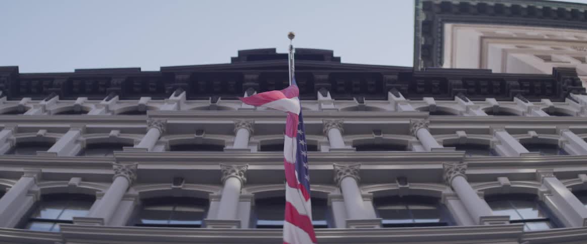 A flag blows on the side of a building