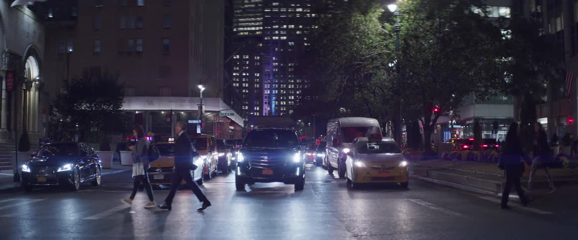 People and traffic pass through a busy city intersection at night