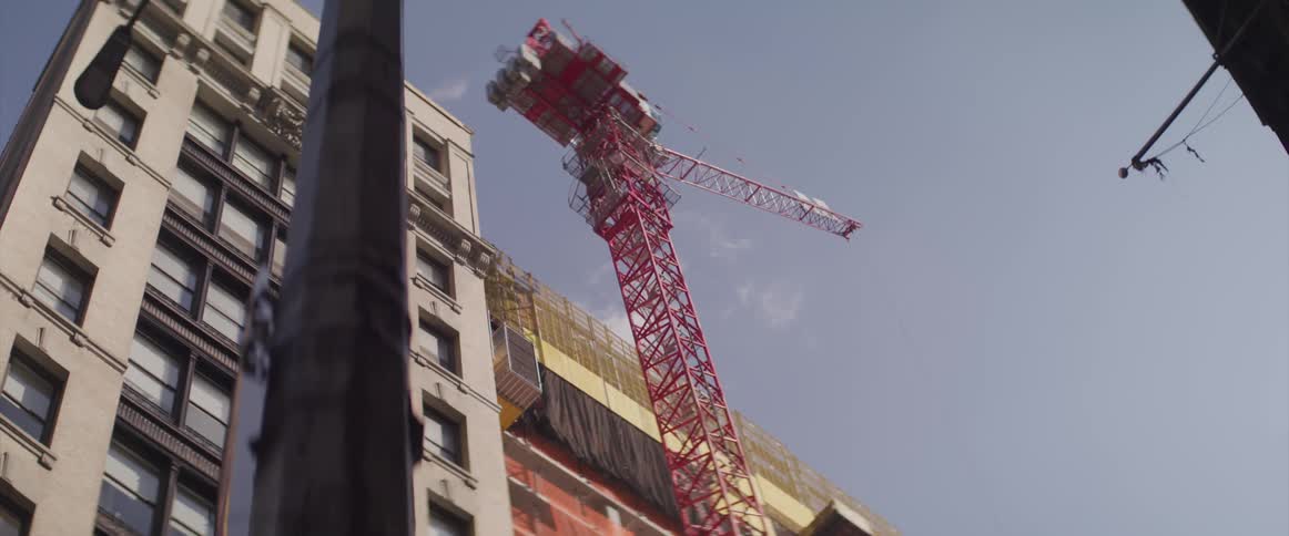 Red crane towers over streetlight near tall building