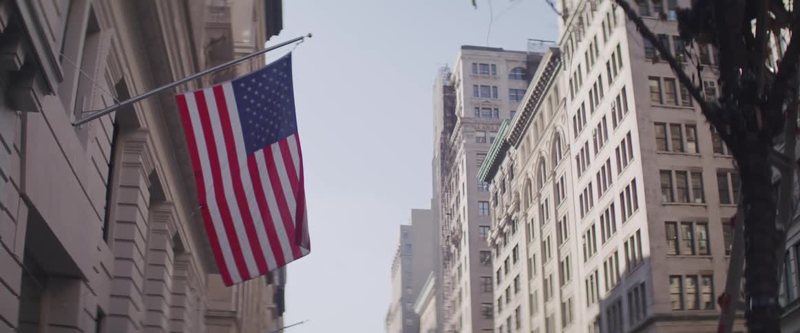 A flag hangs from the side of a building in a citys downtown