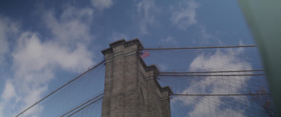 A bridge with an american flag on top with the sky above