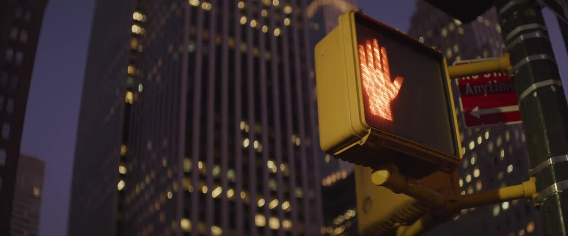 The traffic light in front of the building is blinking stop