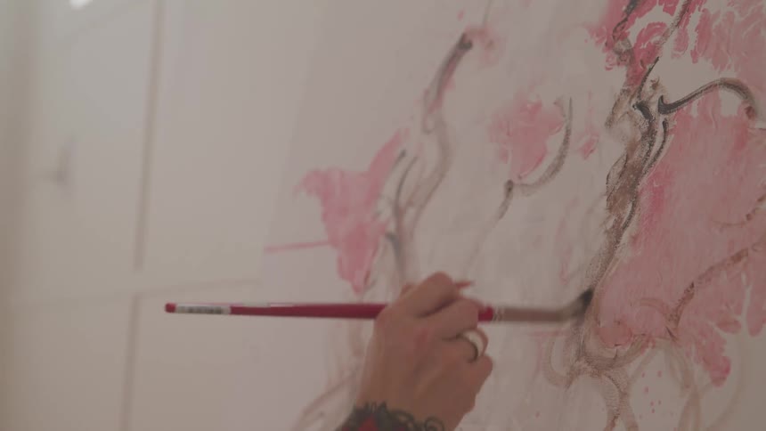 A person paints a canvas with a paint brush