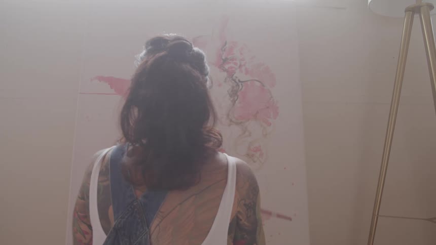 A woman painting on a canvas indoors during the day