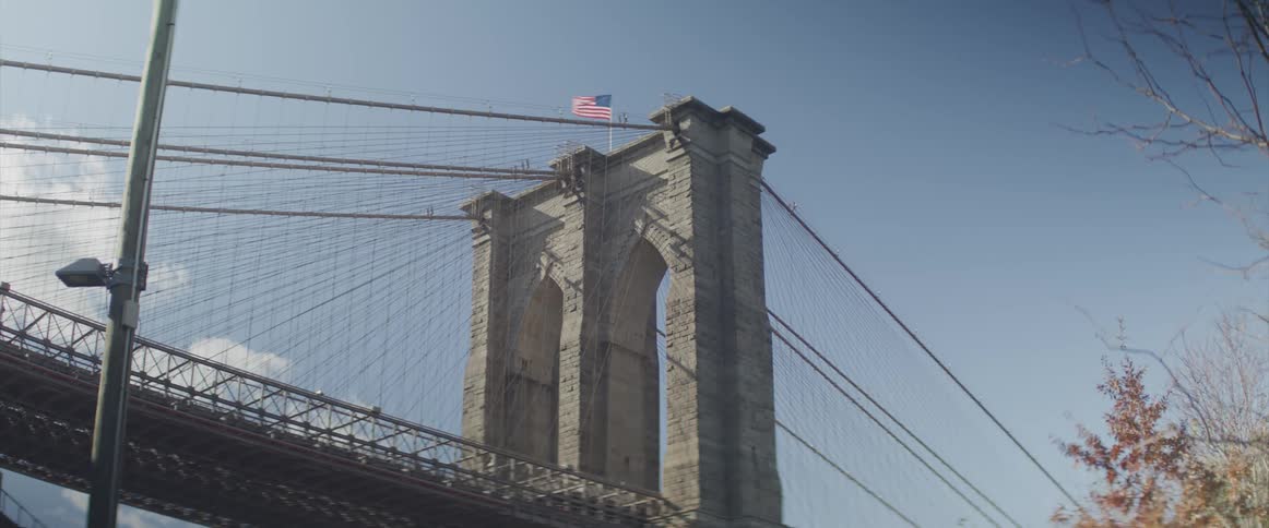 A flag flies atop a suspension bridge tower