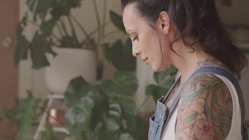 The woman stands near plants